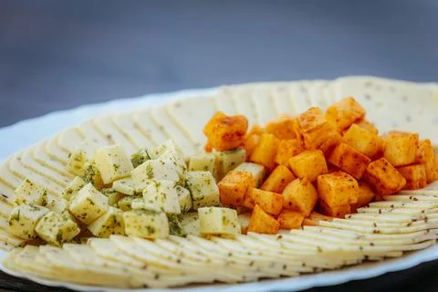 Close-up of a cheese platter featuring spiced and herbed cheese cubes Stock Photos