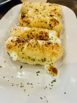 Close-Up of Cheesy Garlic Breadsticks on a White Plate Foto stock