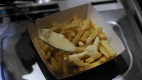 Close-Up of Chef Adding Cheese Sauce to Fries for Customer Stock-Footage 307087009
