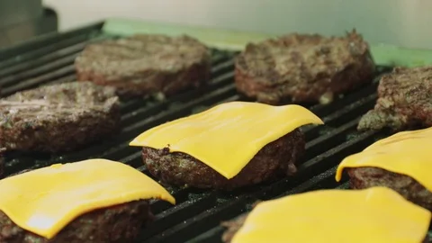 Close up of chef adding cheese on top of hamburger patties sitting on a hot g Stock Footage 127715986
