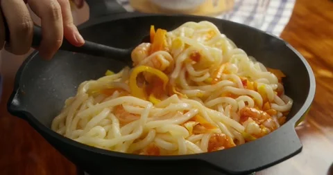 Close up of a chef adding cooked noodles to a pan with shrimp, carrot, yellow Stock-Footage 336210475