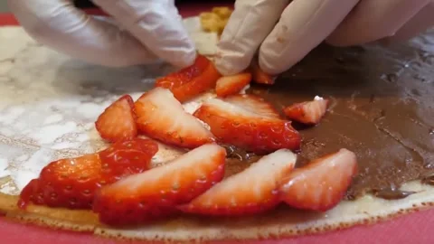 Close-Up of Chef Adding Fresh Strawberry Slices to a Chocolate and Cream Crêpe 스톡 동영상 345692044