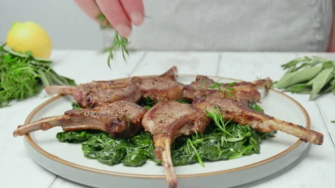 Close-up Chef adding greens on top of cooked lamb ribs cutlets in a plate in 4K. Stock Footage 146001498