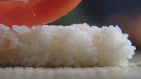 Close-up of chef adding a slice of raw salmon to a rice roll and making sushi Stock Footage 149094049
