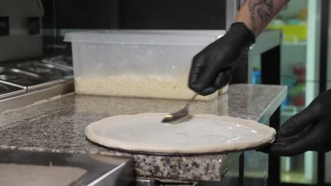 Close-up of the chef applying white sauce to the pizza dough in the kitchen. Stock Footage 344038334