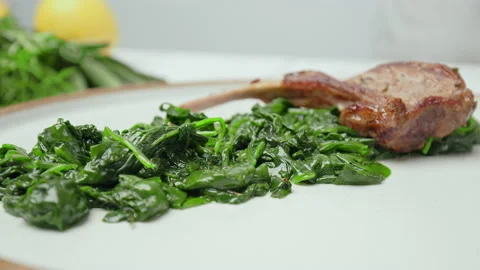 Close-up Chef arranging nicely cooked lamb ribs cutlets into serving plate in 4K Stock Footage 146001102