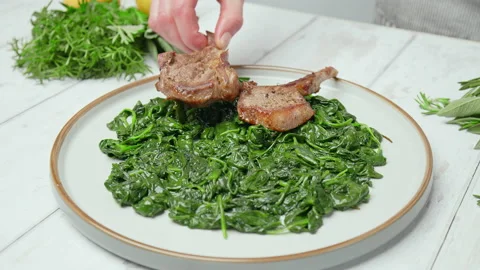 Close-up Chef arranging nicely cooked lamb ribs cutlets into serving plate in 4K Stock Footage 146001566