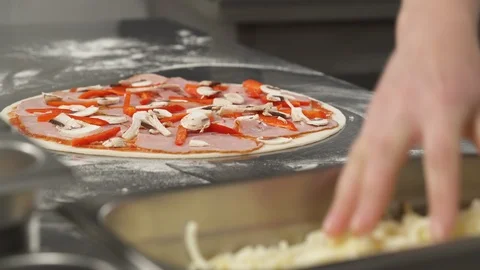 Close-up of chef baker making pizza at professional kitchen. Cheese fall on Stock Footage 121406928