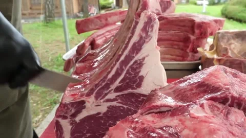 Close-up of a chef in black gloves cutting a raw ribeye tomahawk steak for an ou Stockbeeldmateriaal 338212941