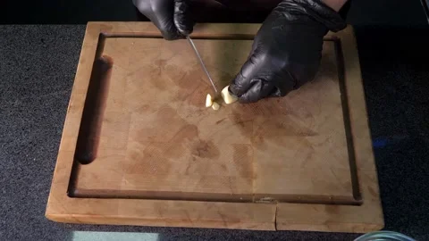 Close-up. A chef in black gloves is slicing garlic for marinade. Delicious Stock Footage 179696705