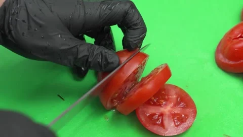 Close-up of Chef in Black Gloves Slicing Fresh Red Tomato on Green Cutting Board Stock Footage 331633552