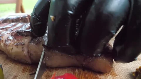 Close-up of a chef in black gloves slicing a juicy, medium-rare grilled beef ste Stock Footage 338210717
