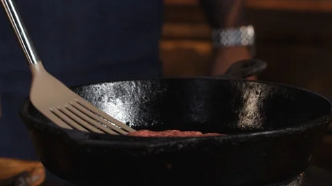Close-up of of chef in blue apron standing near the pan grill and frying cutlet Stock Footage 111592724