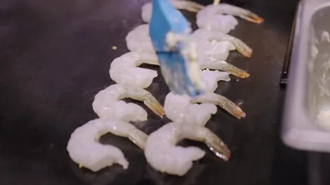 Close-up of Chef Brushing Garlic Butter Sauce on Raw Peeled Shrimps on a Flat Gr Stock Footage 337440422