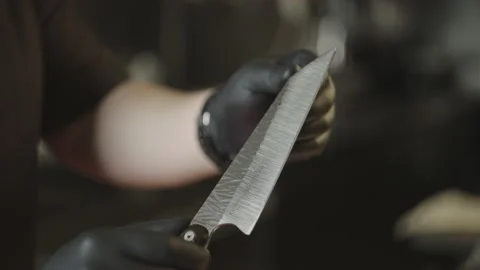 Close-up of a chef checking the sharpness of a knife with his hands. Video stock 233812959