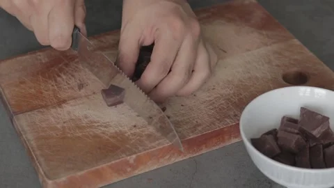A Close up of a chef chopping a bar of chocolate on a wooden table. Slow moti Stock Footage 139321596