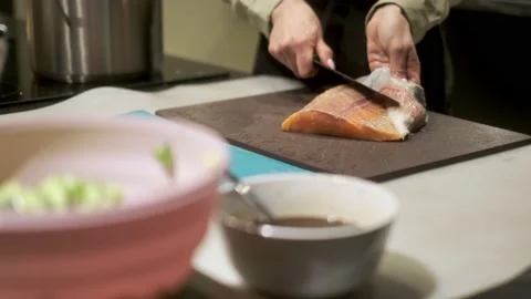 Close-up of a chef cleaning a salmon fillet on a cutting board in the kitchen. Stock Footage 231159366