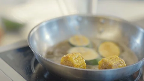 Close up of chef cooker in black gloves friyng or stewing slices of zucchini and Stock Footage 107729701