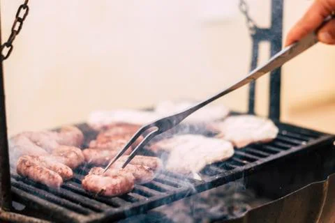 Close up of chef cooking meat on a warm grill - sausages on bbq - home nbarbe Stock Photos