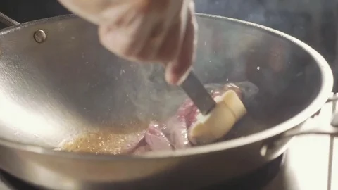 Close-up of chef cooking meat in wok pan. Meat fried in boil butter, slow motion Stock Footage