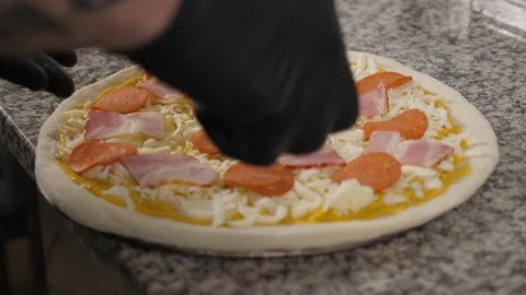 A close-up of a chef cooking pizza, he puts sliced sausage on a dough. Stock Footage 342702701