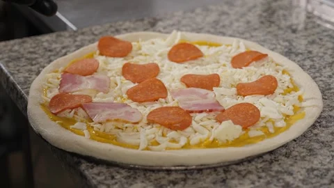 A close-up of a chef cooking pizza, he puts sliced sausage on a dough. Stock Footage 343736320