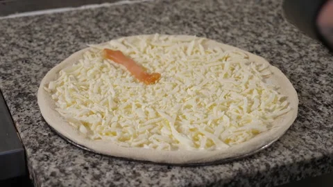 A close-up of a chef cooking pizza, he puts sliced sausage on a dough. Stock Footage 345132798