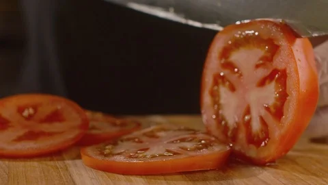 Close-up of chef cut into slices with sharp knife fresh tomato on wooden board Stock Footage 113870096