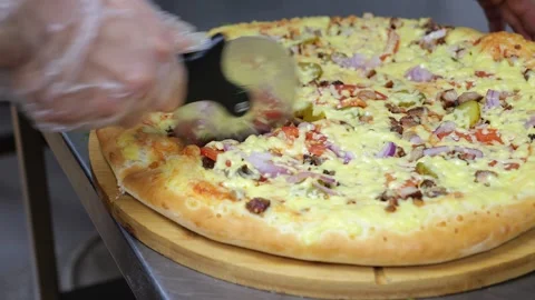 Close-up of a chef cutting a baked pizza with a knife in a restaurant kitchen. Stock Footage 318659291