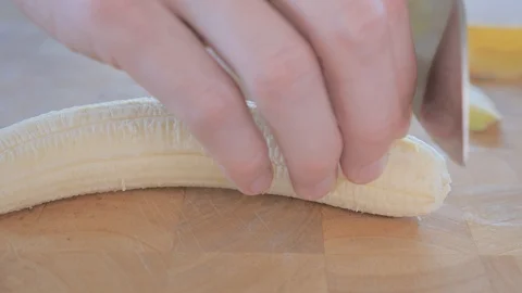 Close-up on chef cutting banana on a cutting board. Stock Footage 105507720