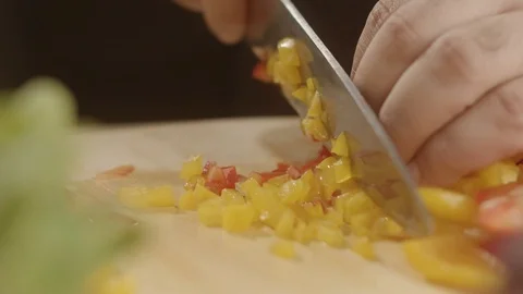 Close-up of chef cutting fresh bell peppers into small squares with sharp knife Stock Footage 113513337