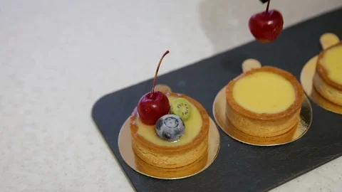 Close up of chef decorating a fresh baked cake with cherry and blueberry Stock Footage 102368875