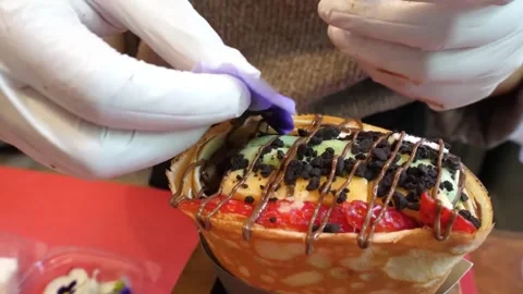 Close Up of Chef Decorating a Loaded Dessert Crepe with Edible Flowers Stock-Footage 345692080