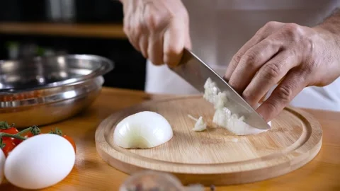 Close-up of a chef dicing onions on a chopping board with a knife. 動画素材 276837056
