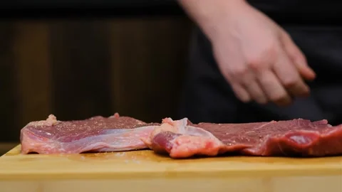 Close-up. The chef flips and salts a beef steak Stock Footage 188540684