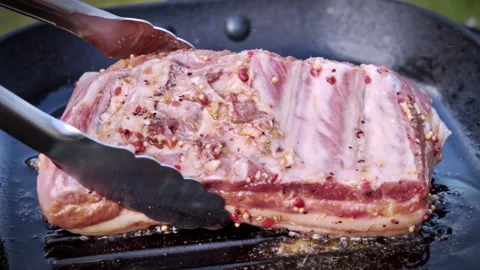 Close-up, chef frying marinated pork ribs on a cast iron pan outdoors. Stock Footage 315280608