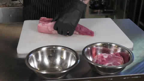 Close-up of a chef in gloves cutting fresh pork ribs with a knife. Stock Footage 287583985