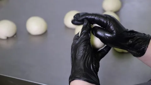 Close-up of a chef in gloves forming balls of yeast dough for buns. Stock Footage 318658809