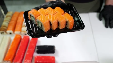 A close-up chef in gloves holds a plate of sushi in the restaurants kitchen. Stock Footage 322215496