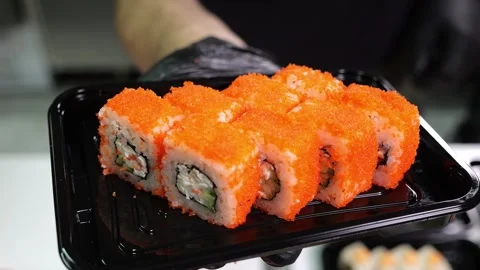 A close-up chef in gloves holds a plate of sushi in the restaurants kitchen. Stock Footage 322215574