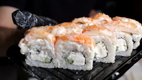 A close-up chef in gloves holds a plate of sushi in the restaurants kitchen. Stock Footage 323362778