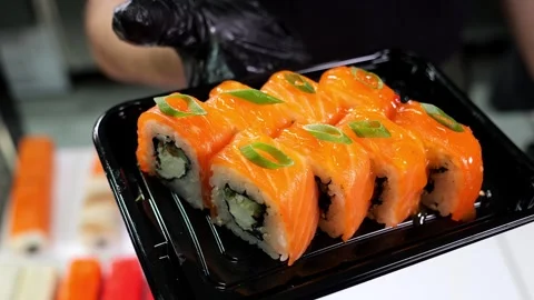 A close-up chef in gloves holds a plate of sushi in the restaurants kitchen. Stock Footage 325180854