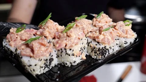 A close-up chef in gloves holds a plate of sushi in the restaurants kitchen. Stock Footage 327273727