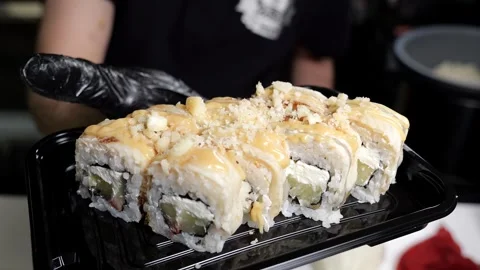 A close-up chef in gloves holds a plate of sushi in the restaurants kitchen. Stock Footage 329403242