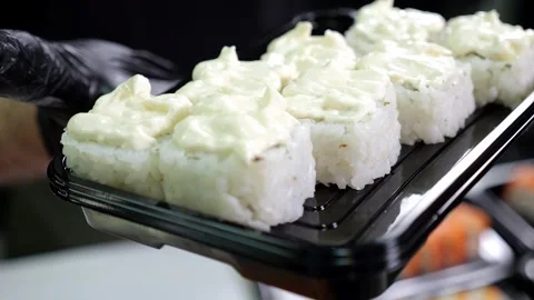 A close-up chef in gloves holds a plate of sushi in the restaurants kitchen. Stock Footage 346442582
