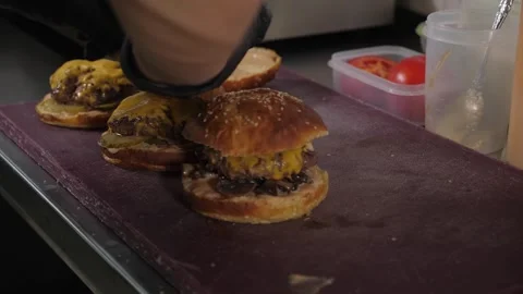 A close-up of a chef in gloves putting buns with sauce on burgers with fried egg Video stock 343736514