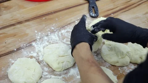 Close-up of a chef in a gloves rolling out dough with a rolling pin in a kitchen Stock Footage 341550353