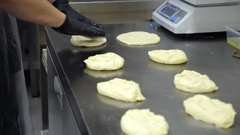 Close-up of a chef in a gloves rolling out dough with a rolling pin in a kitchen Stock Footage 341550436