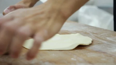 Close-up of a chef in a gloves rolling out dough with a rolling pin in a kitchen Stock Footage 341550495