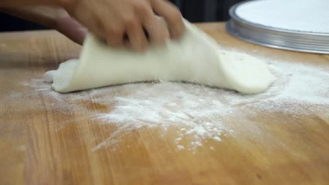 Close-up of a chef in a gloves rolling out dough with a rolling pin in a kitchen Stock Footage 341550612
